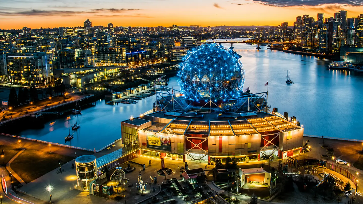 Science World illuminated beside False Creek at sunset